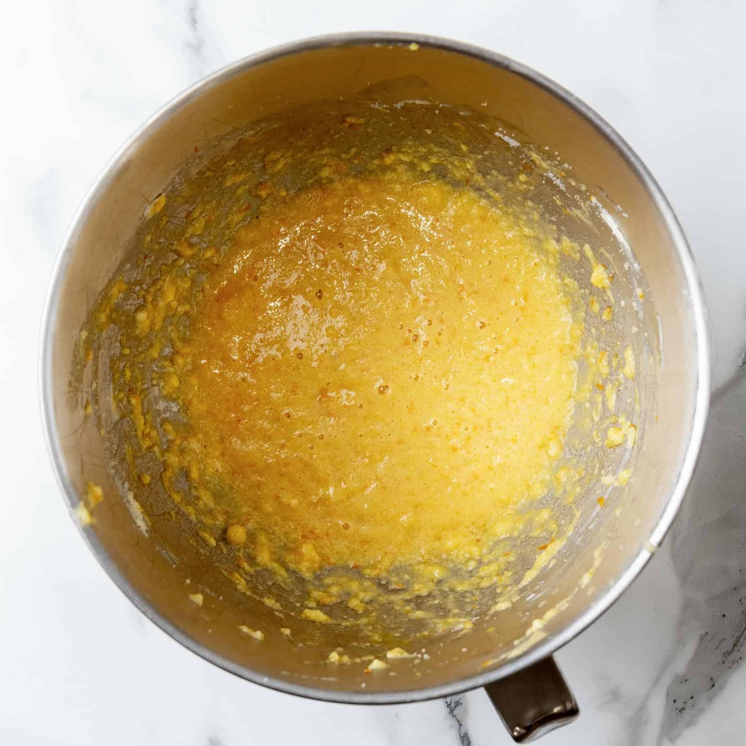 Wet ingredient mixture for Orange cupcakes, in the bowl of a stand mixer.