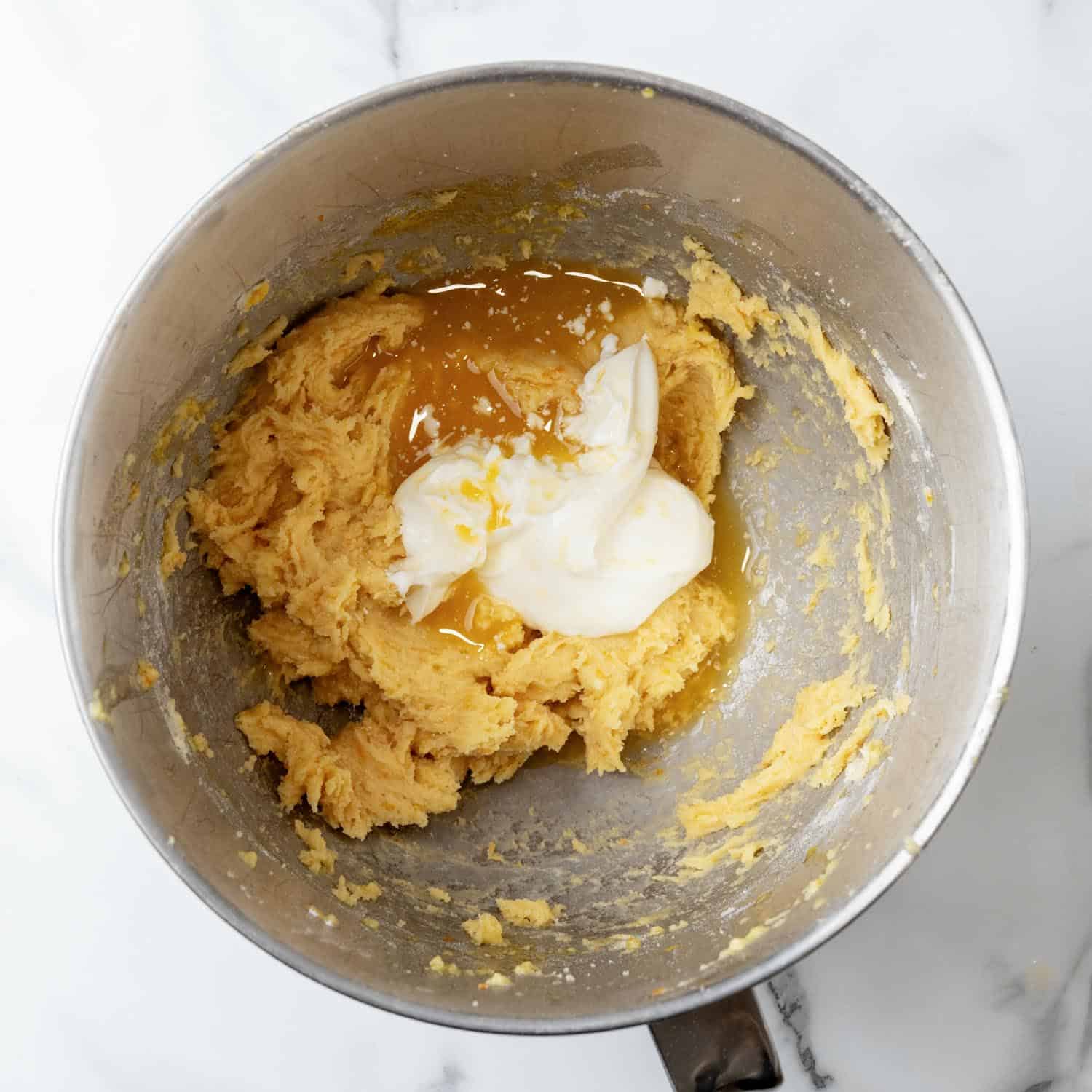 Sour cream and orange juice added to orange cupcake batter in a mixing bowl