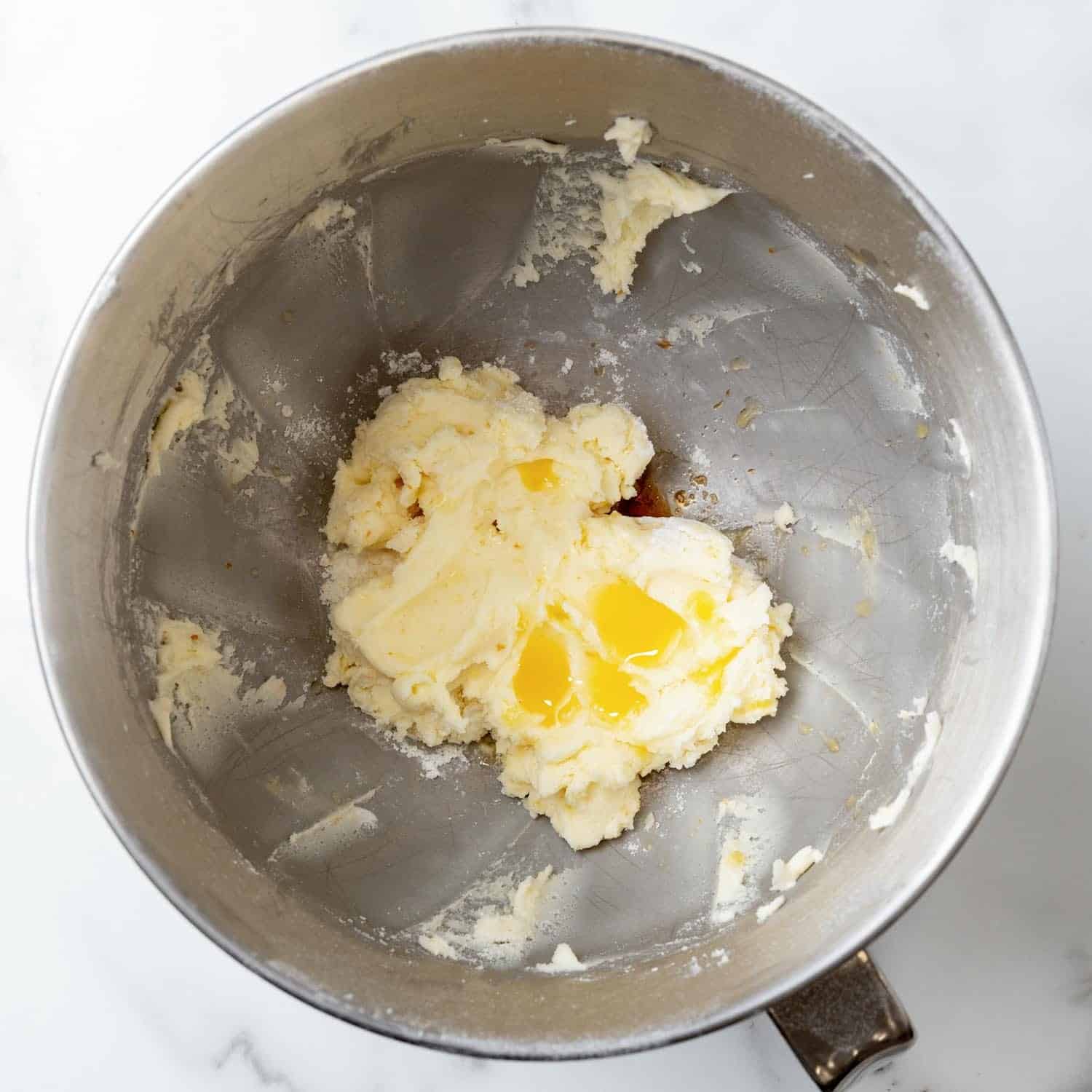 Orange juice and vanilla added to buttercream frosting in a mixing bowl.