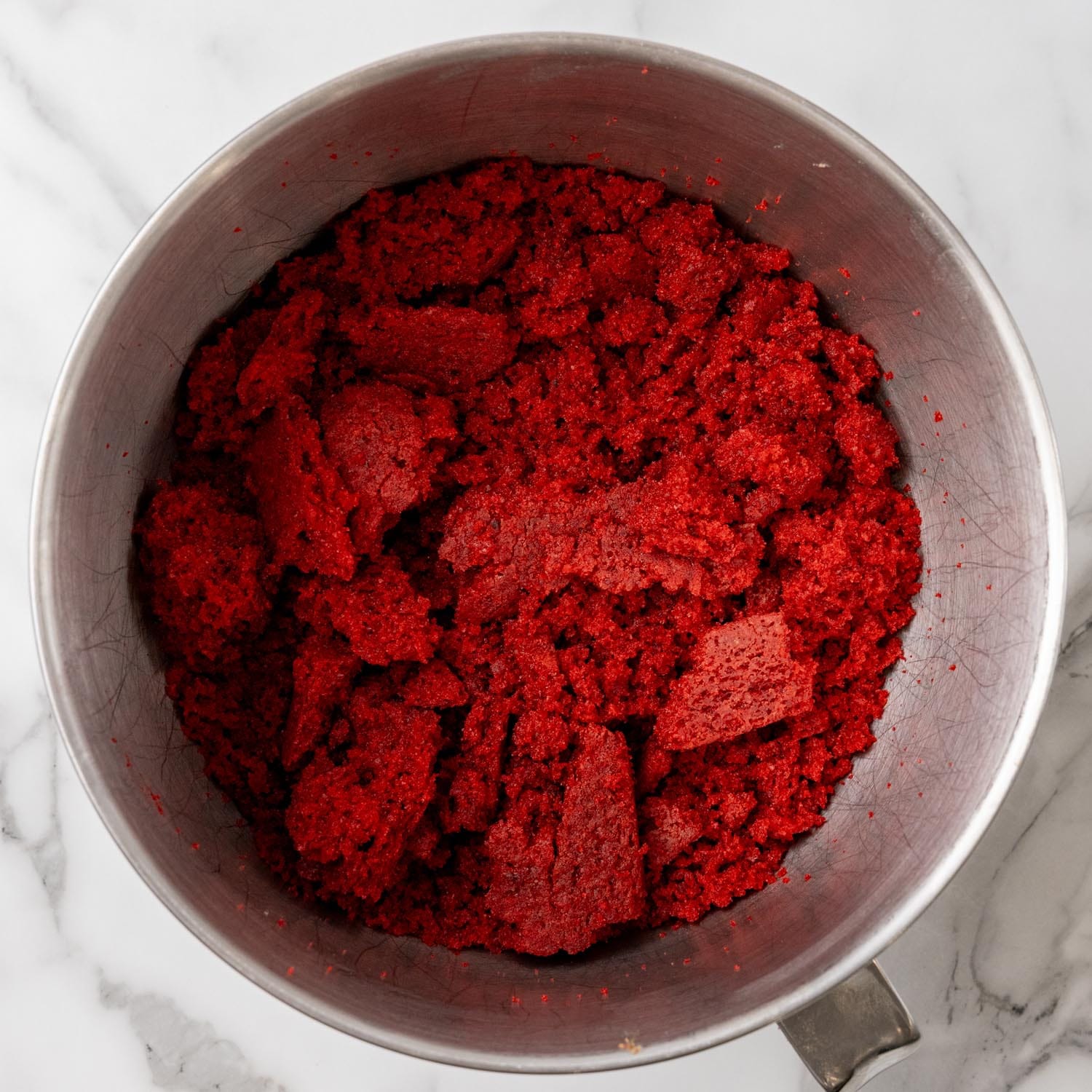 crumbled red velvet cake in a stand mixer bowl.