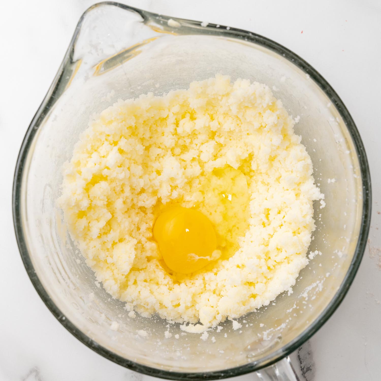 raw egg added to creamed butter and sugar in a glass pyrex bowl.