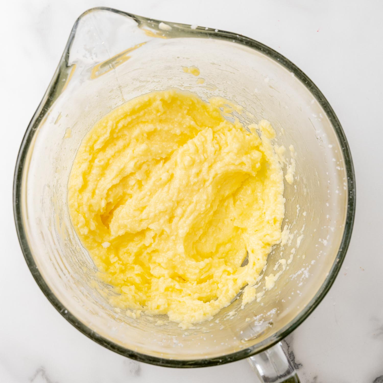 Cake batter beginnings with butter, sugar, and eggs, in a glass mixing bowl.