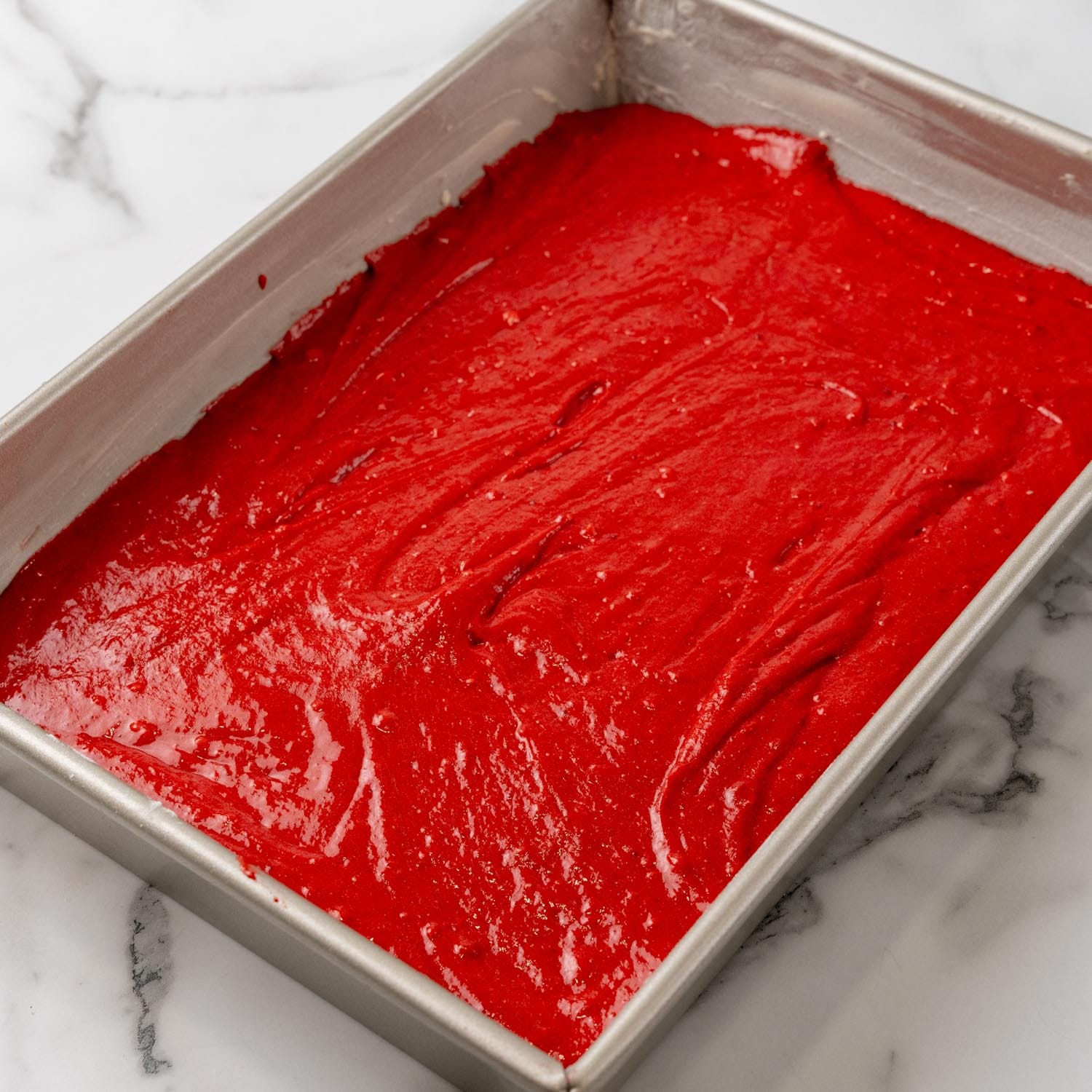 red velvet cake batter poured into a 9x13 greased pan.