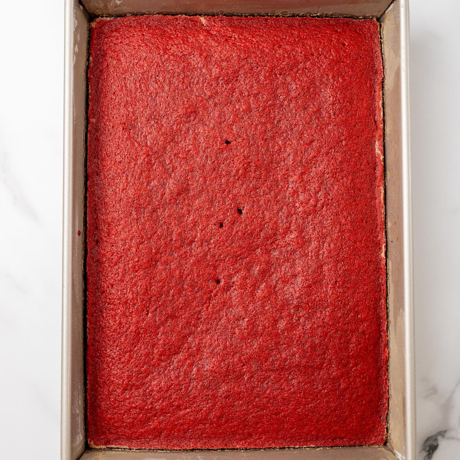 red velvet cake baked in a metal 9x13 pan.