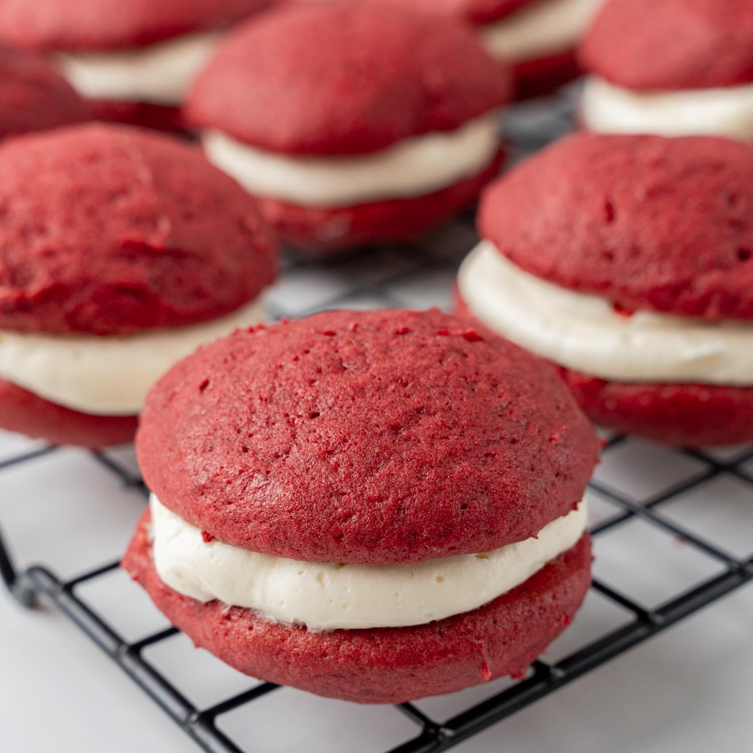 closeup of red velvet cake whoopie pies on a cooling rack.