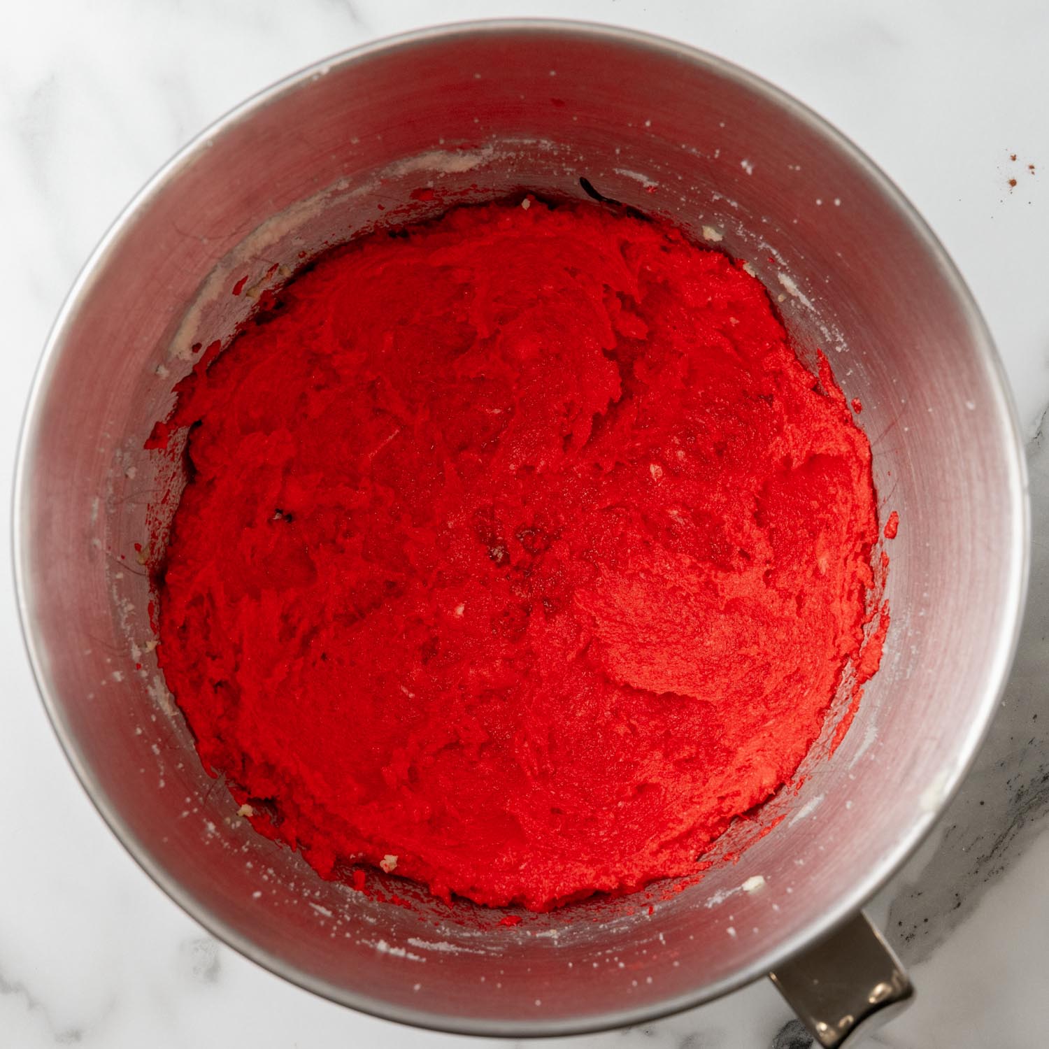 bright red cake batter for red velvet whoopie pies, in a metal mixing bowl.