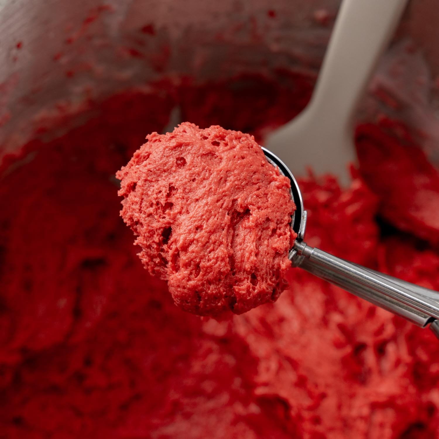 a cookie scoop filled with red velvet whoopie pie cake batter.