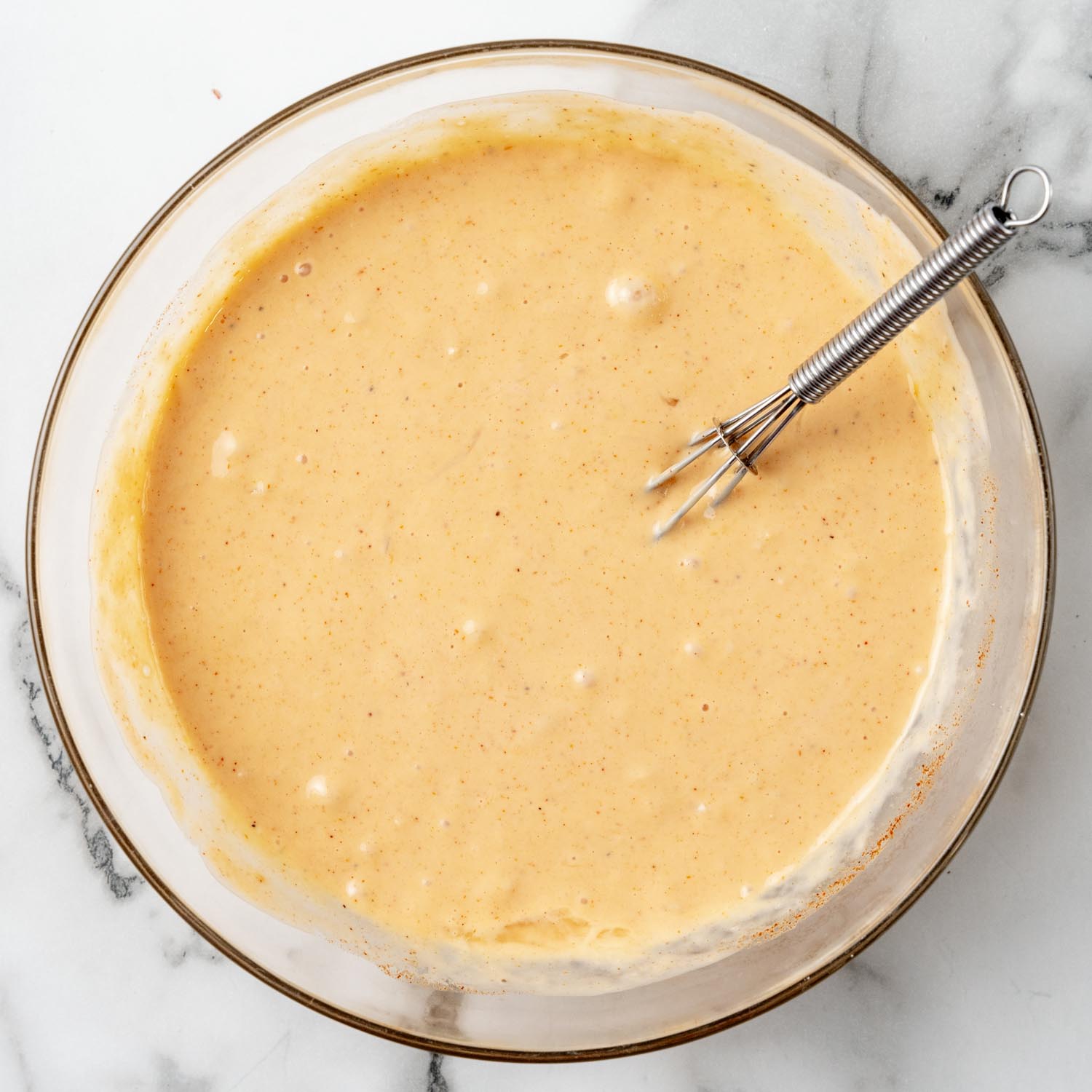 Mayo based sauce for Reuben casserole in a small glass bowl with a whisk.