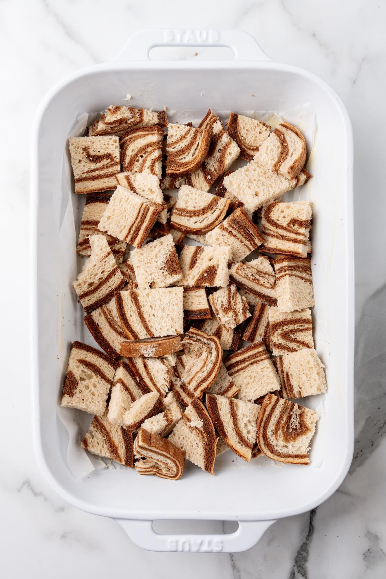 Cubes of marble rye bread in a 9x13 pan to make the base layer for a Reuben casserole.