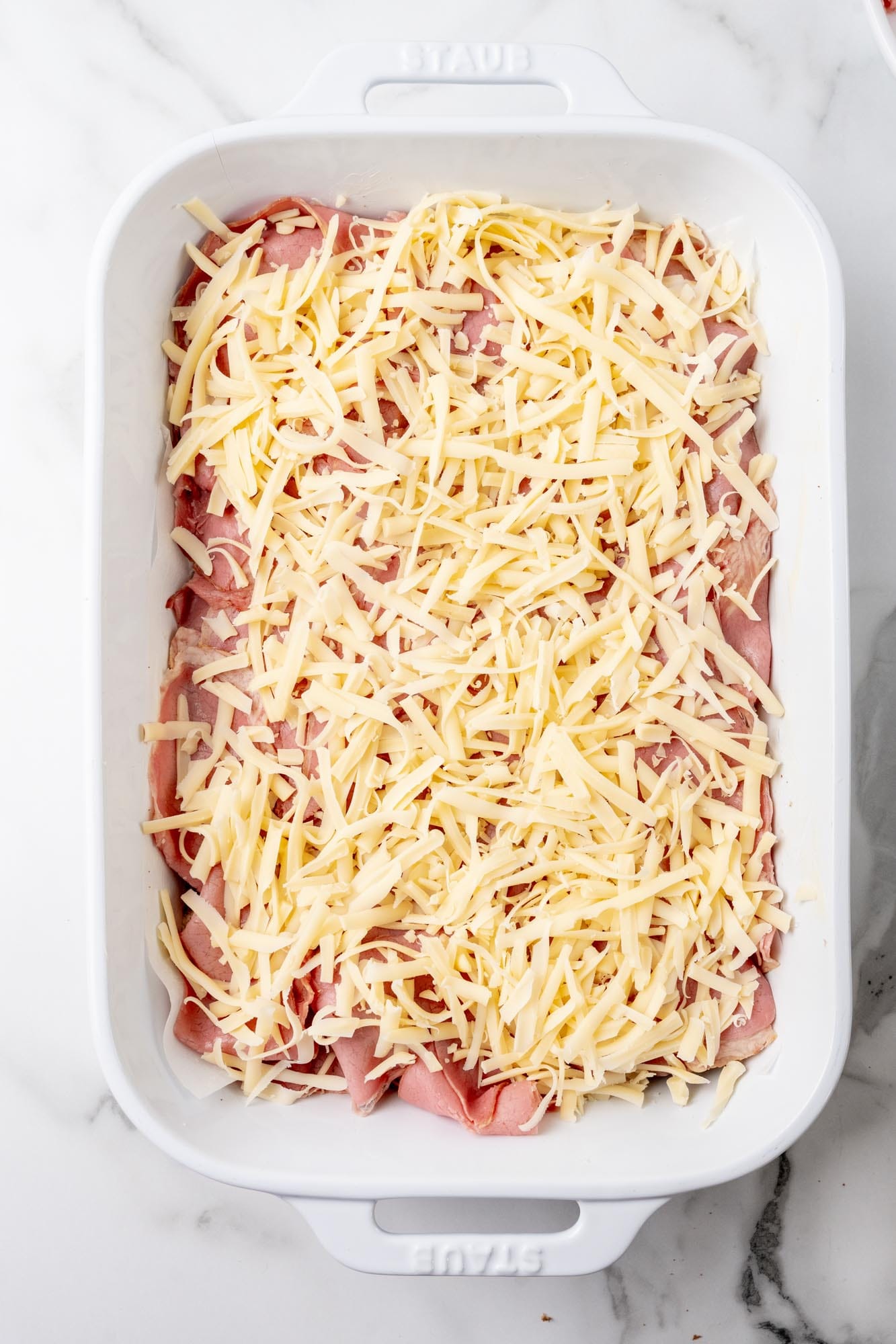 Layers of corned beef and swiss cheese in a casserole pan.