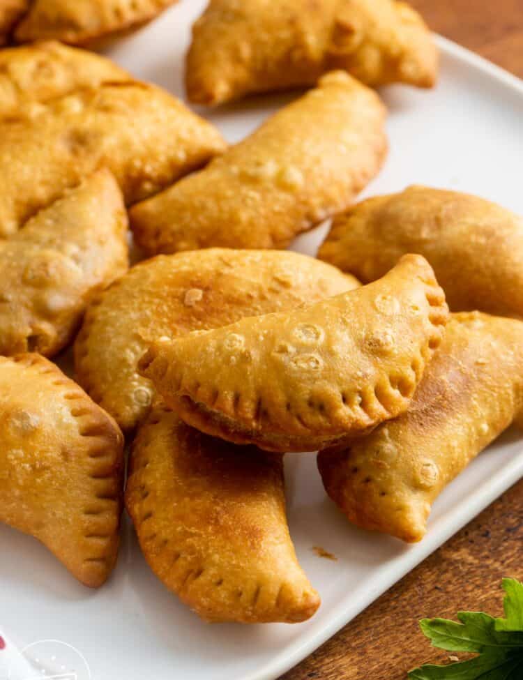 a square white plate holding fried sambousek appetizers.