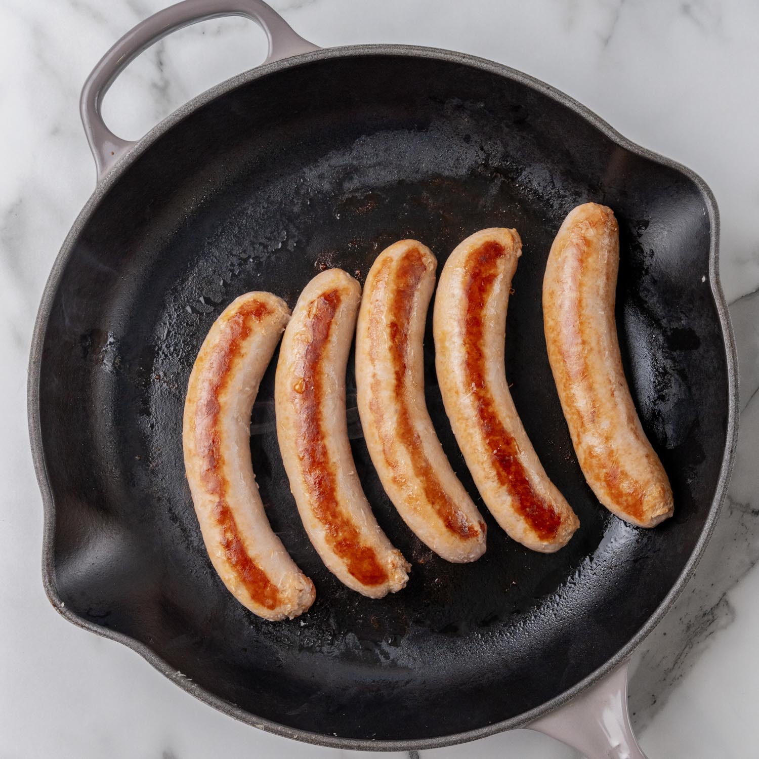 5 italian sausage links, browning in a cast iron skillet.