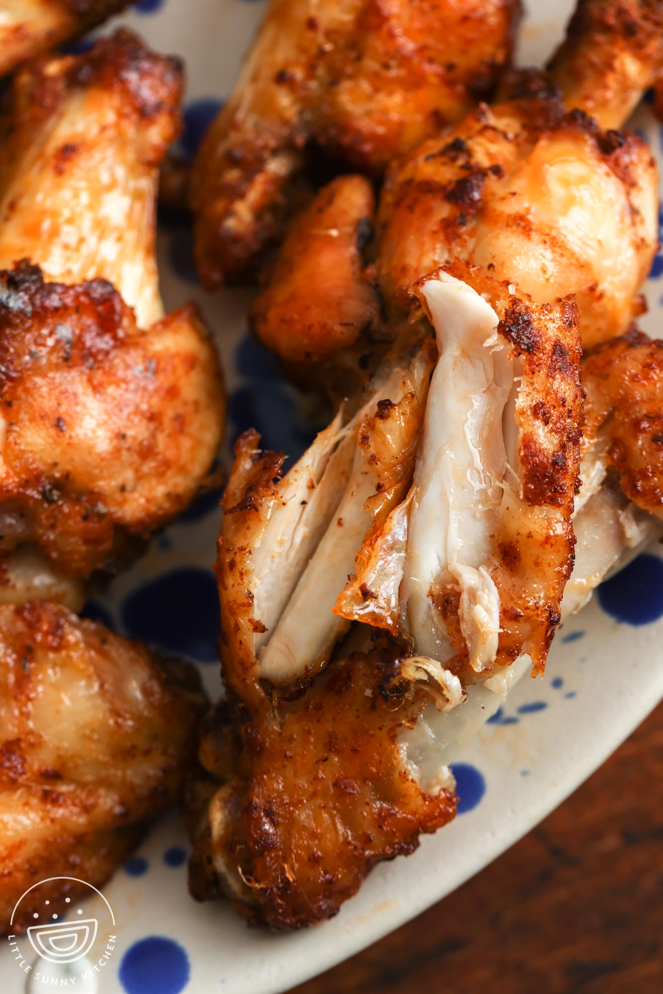 closeup of an air fryer chicken wing that has been pulled apart to show the tender meat inside.