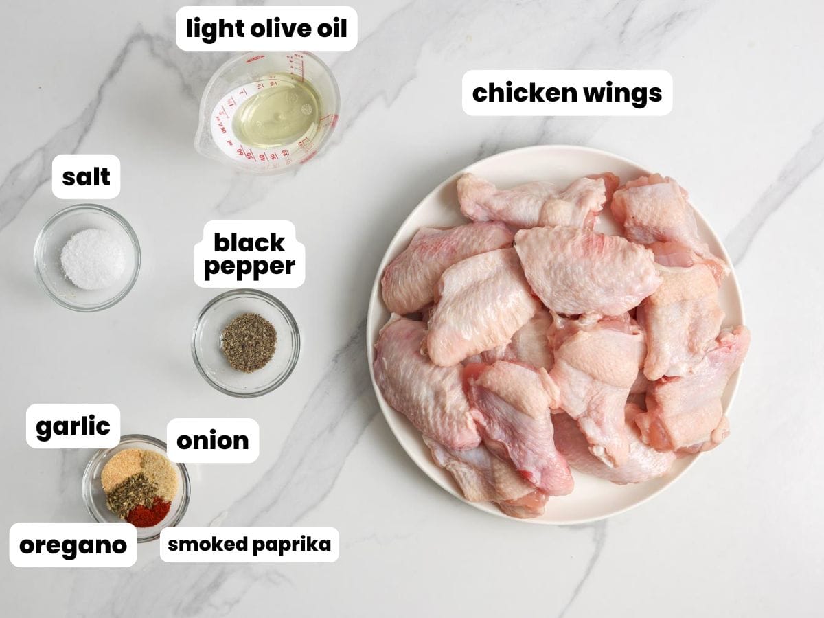 The ingredients for making air fryer chicken wings, including raw fresh wings, olive oil, and seasonings.