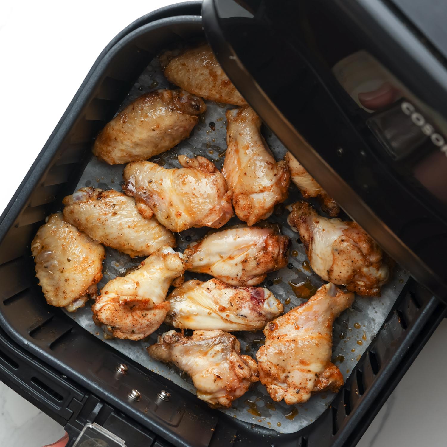 half cooked chicken wings in a cosori air fryer.