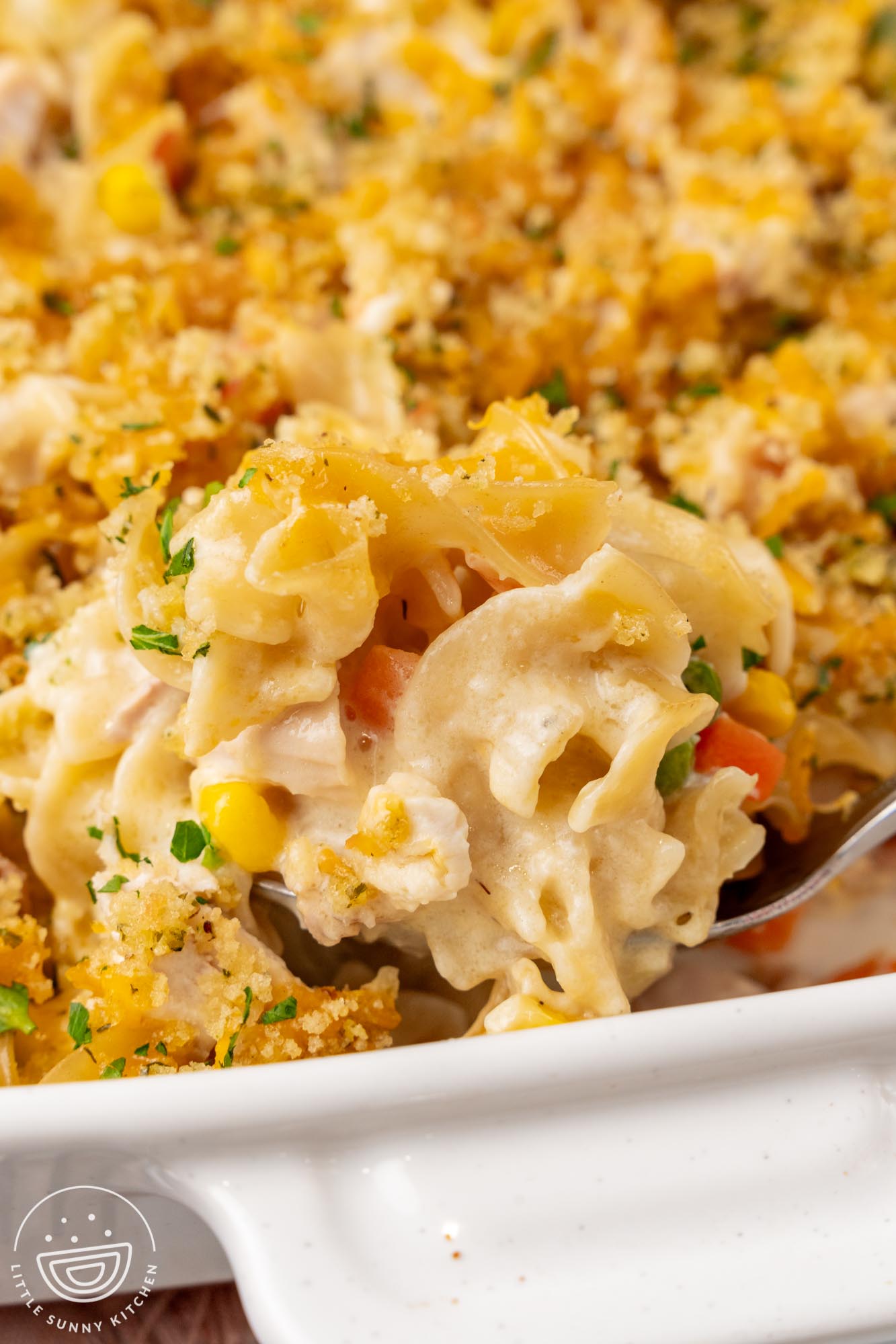 Closeup of a spoonful of chicken noodle casserole showing egg noodles in a creamy sauce with vegetables.