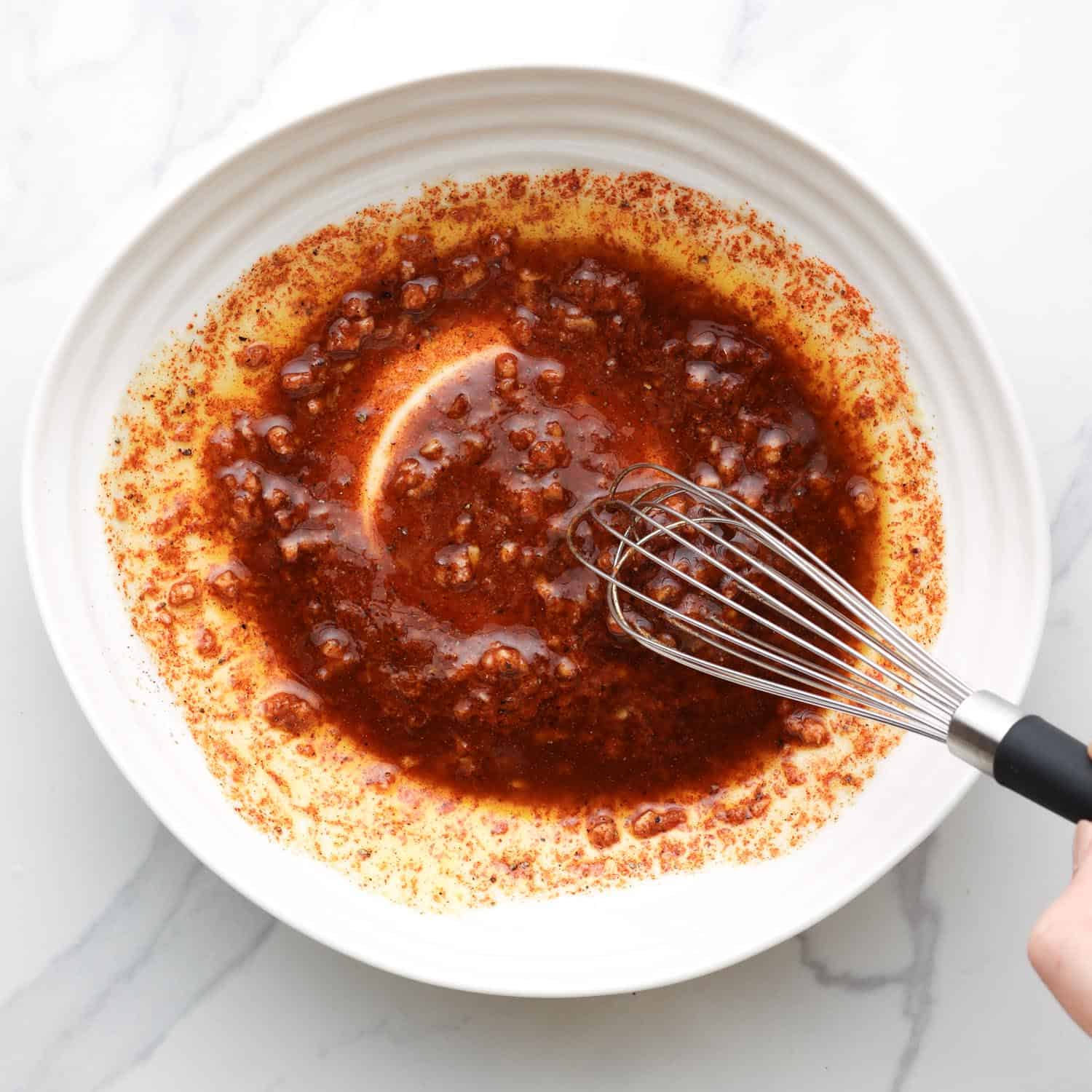 red shawarma marinade, whisked in a shallow ceramic dish. 