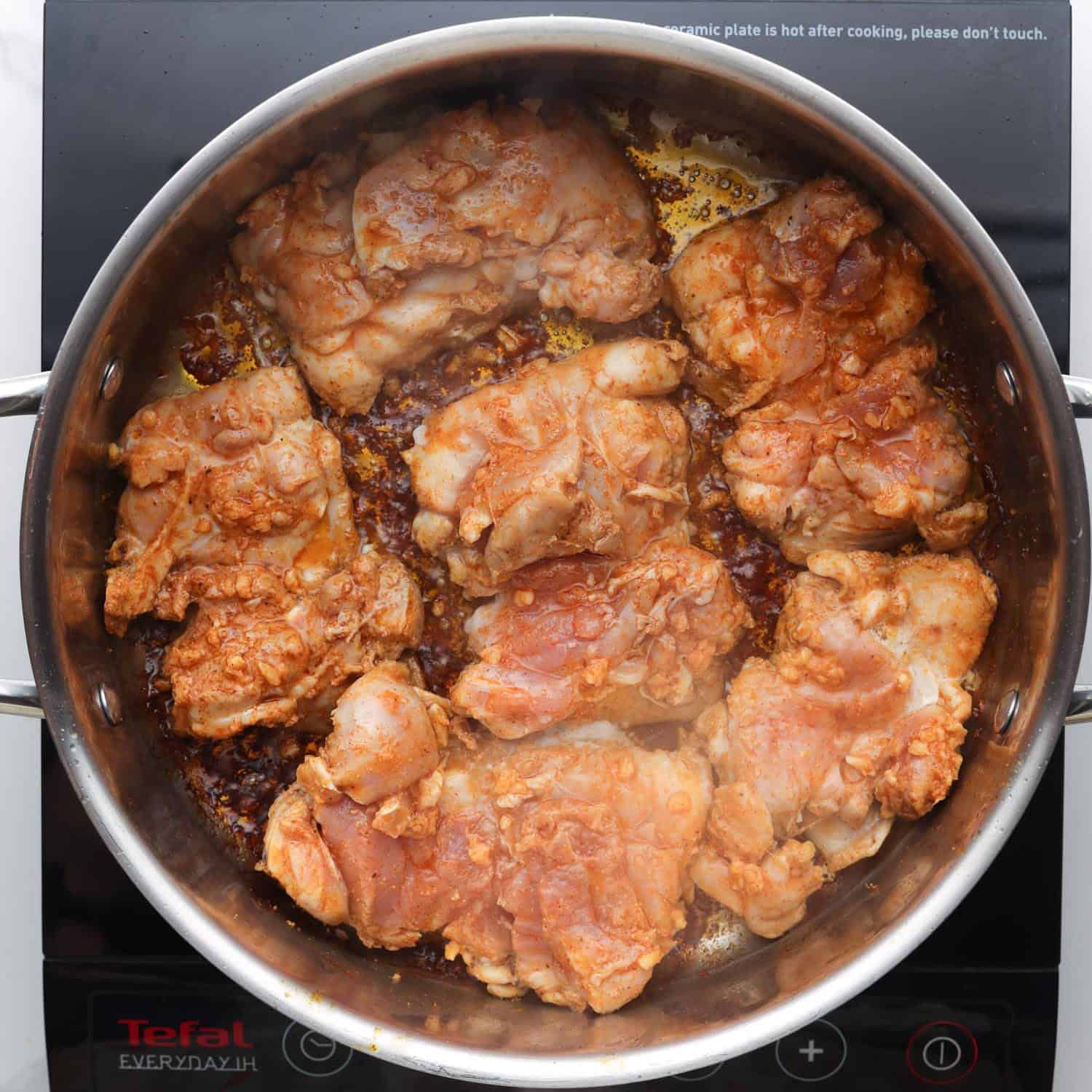 marinated chicken thighs searing in a skillet. 