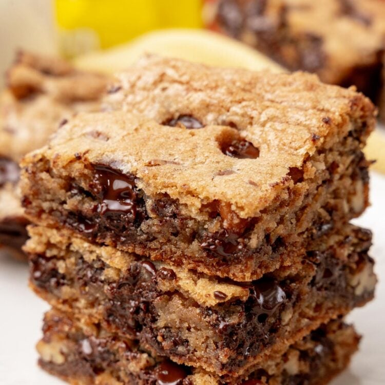 a stack of three chocolate chip cookie bars on a white plate.