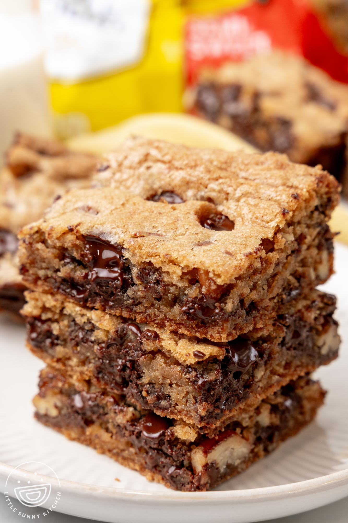 a stack of three chocolate chip cookie bars on a white plate.