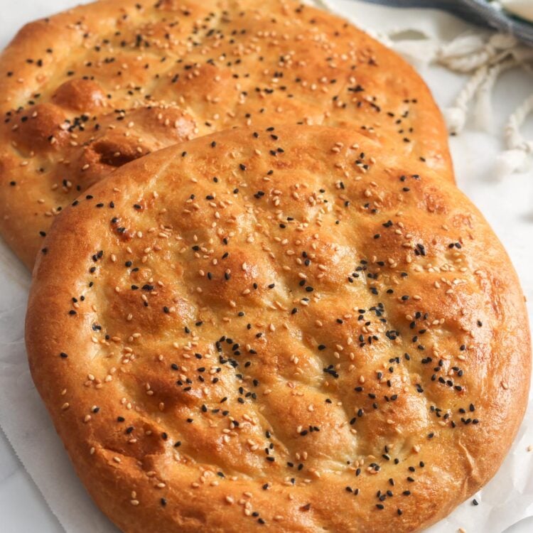 two loaves of pillowy ramazan pidesi topped with sesame seeds and nigella seeds