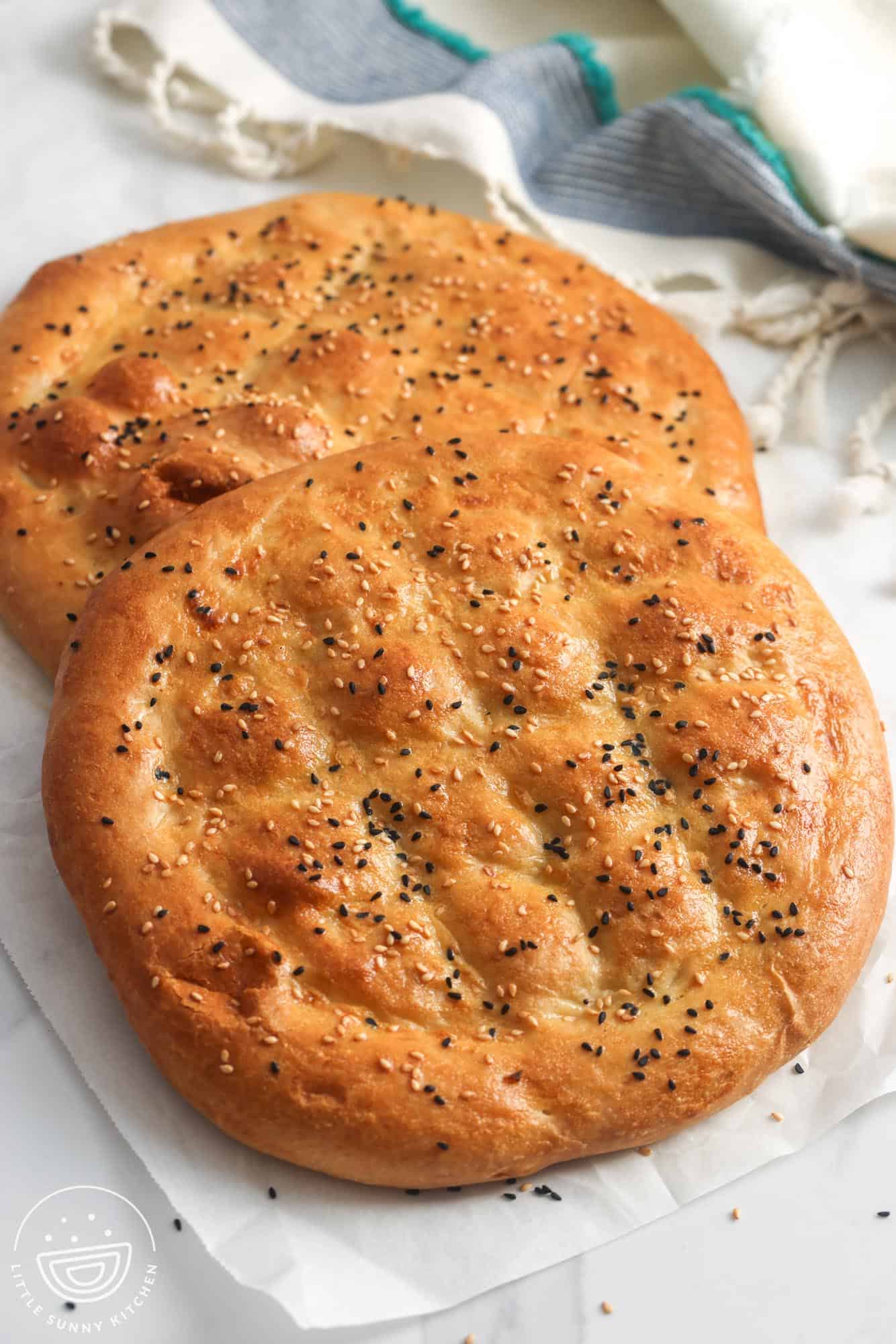 two loaves of pillowy ramazan pidesi topped with sesame seeds and nigella seeds