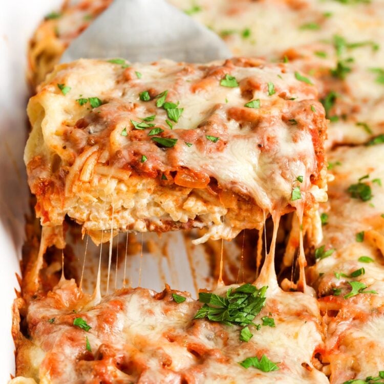 a spatula lifting up a square piece of cream cheese spaghetti casserole.