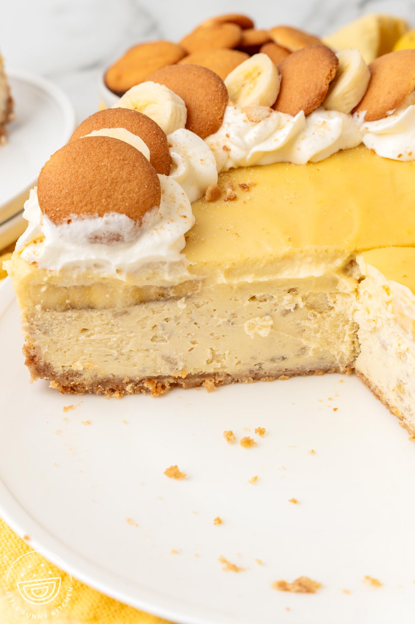 A banana pudding cheesecake on a platter with slices removed.