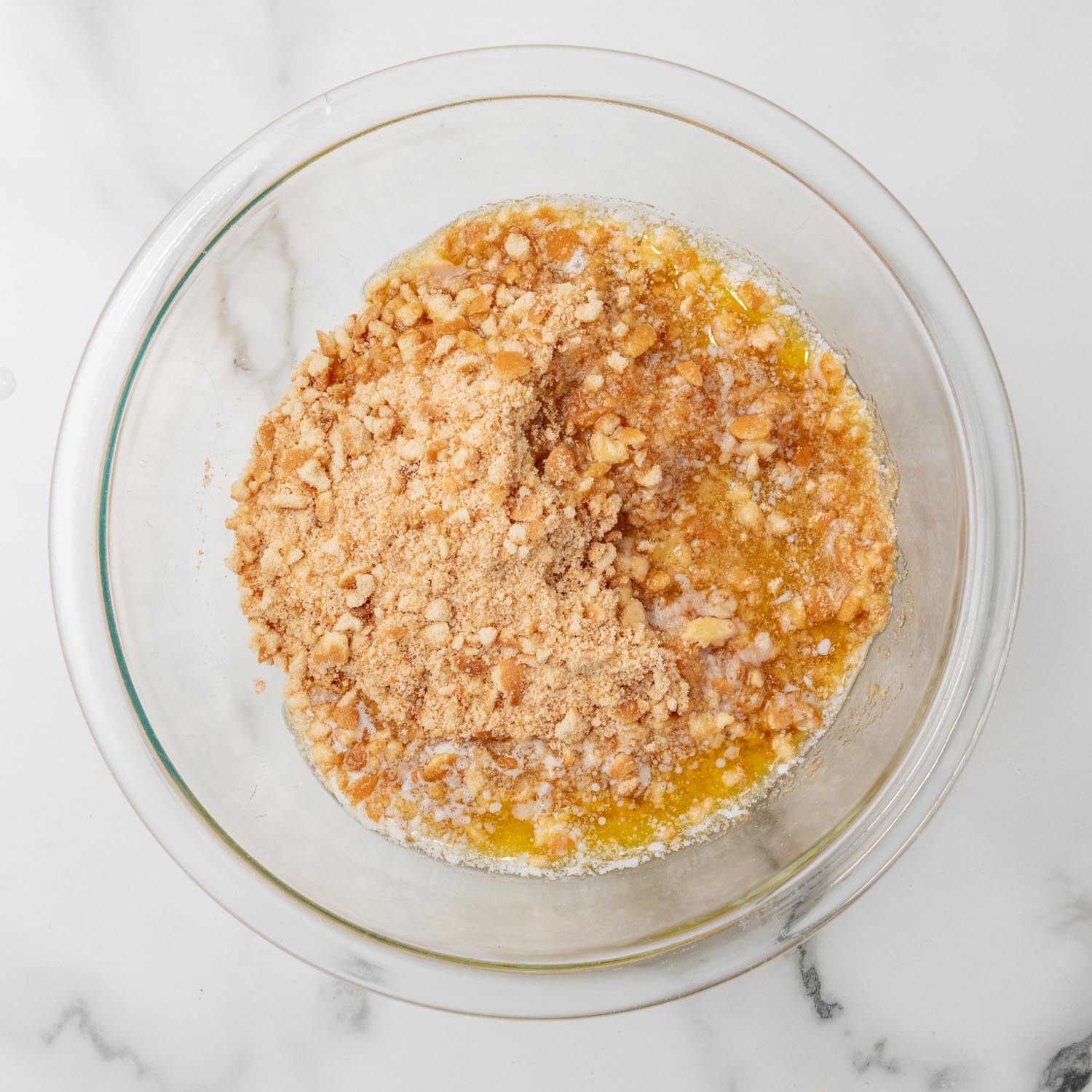 crushed vanilla wafers in a glass bowl with melted butter.