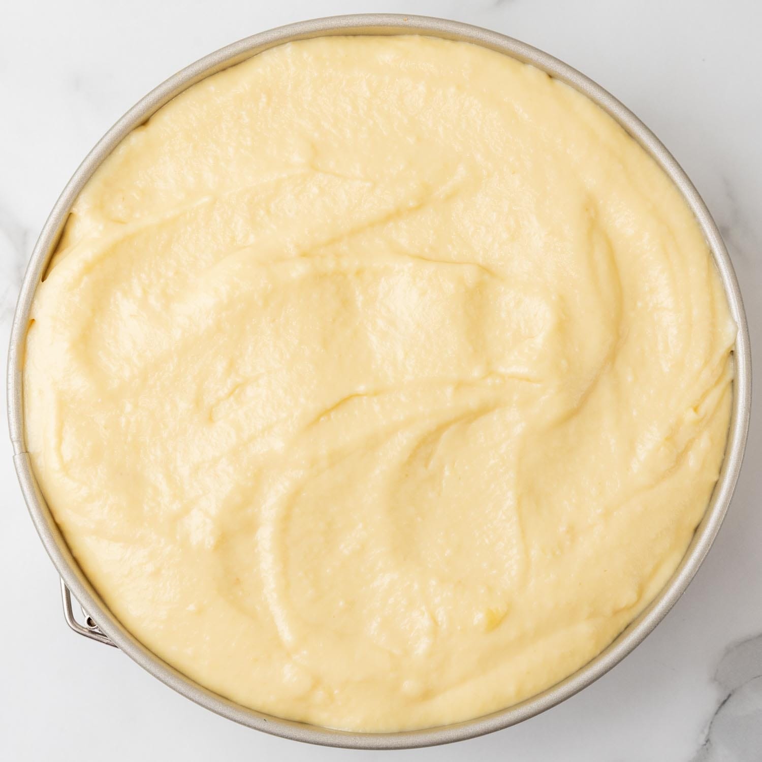 banana pudding cheesecake batter added to a springform pan, viewed from overhead.