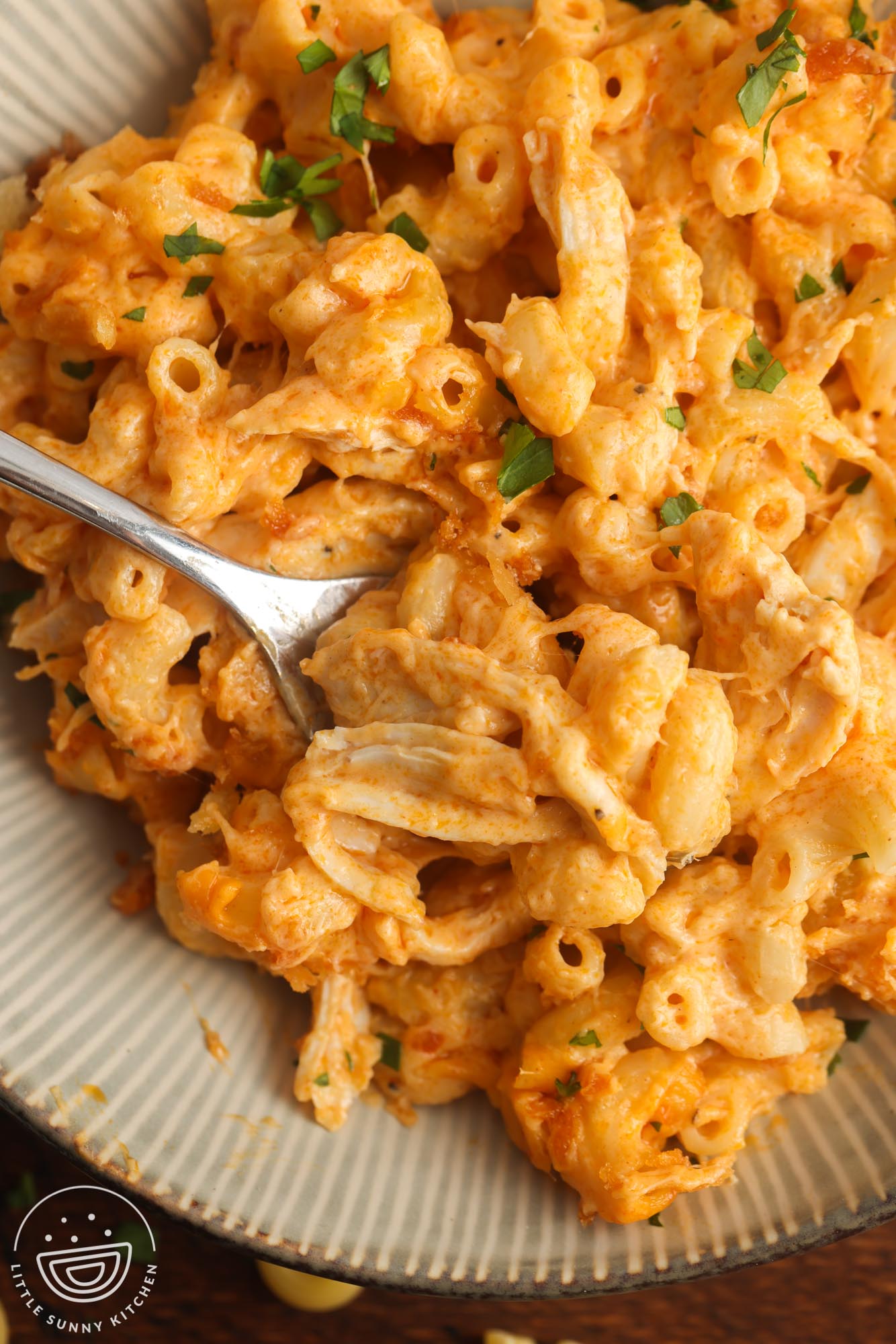 closeup of a bowl of buffalo chicken mac and cheese with a fork.