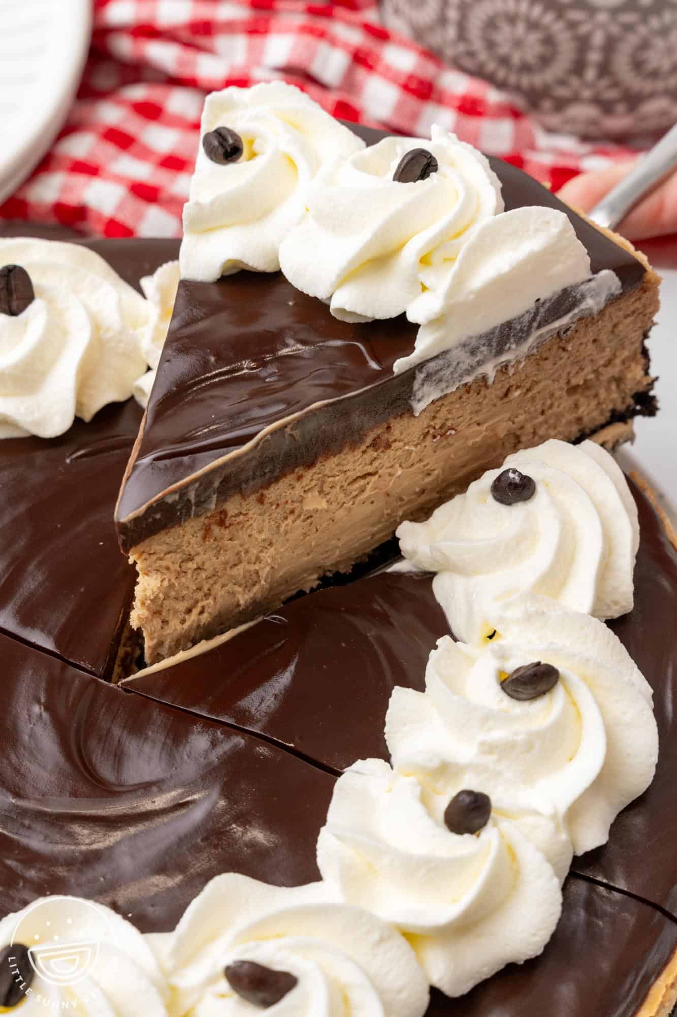 a slice of coffee cheesecake lifted up from the whole pie to show the creamy texture.