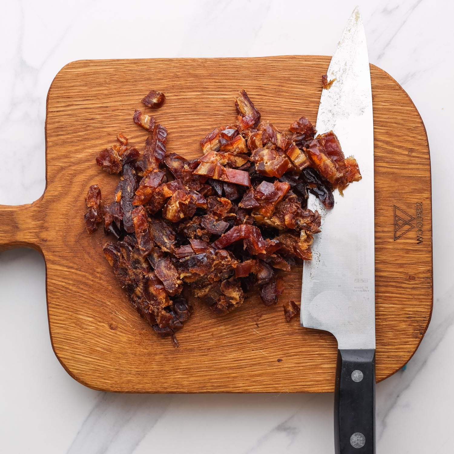 chopped dried dates on a cutting board with a large chefs knife.