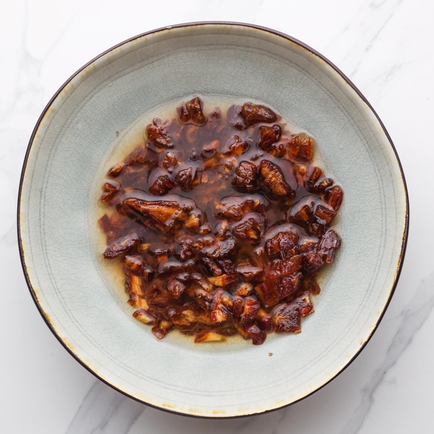 dried dates soaking in boiling water in a large ceramic bowl.