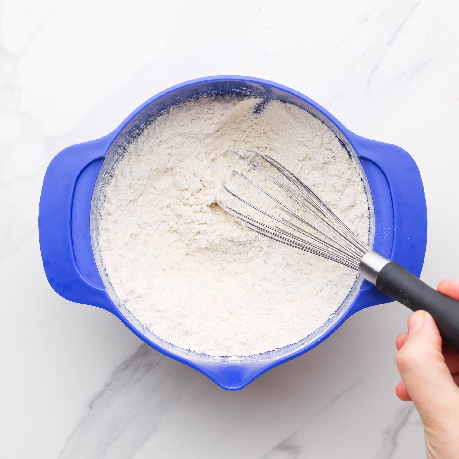 dry ingredients for date bread whisked in a small purple bowl.