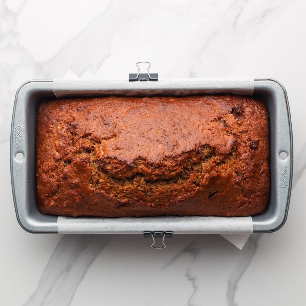 baked date bread in a metal loaf pan.