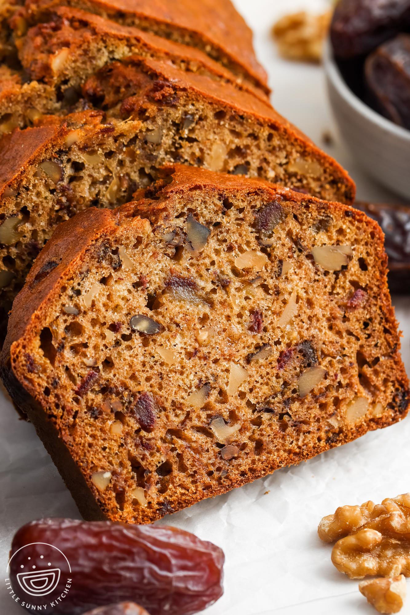 closeup of sliced date nut bread showing the tender crumb and large pieces of nuts and dates inside.