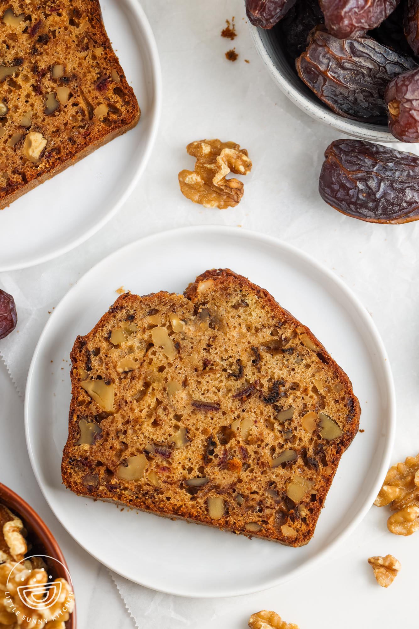 a slice of bread with dates and walnuts on a white plate.