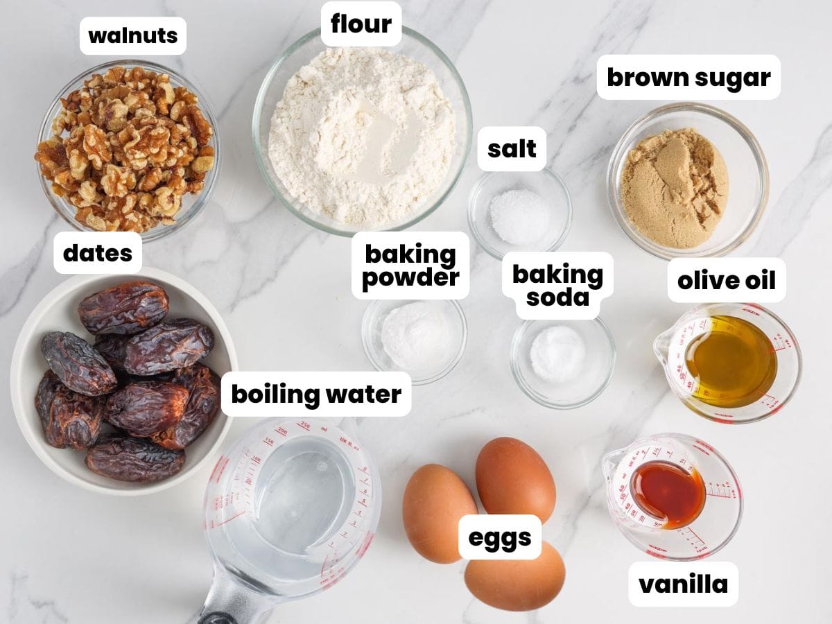 Ingredients for date nut bread with walnuts, measured into small glass bowls and arranged on a marble counter.