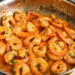 a skillet of cooked shrimp in harissa garlic sauce.