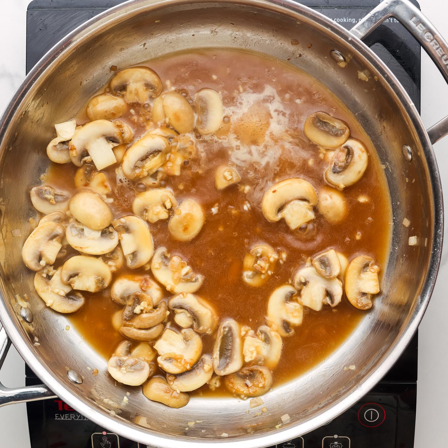 broth added to a pan of mushrooms to create a sauce.