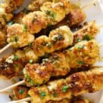 a platter of chicken spiedini skewrs with a side of sauce.