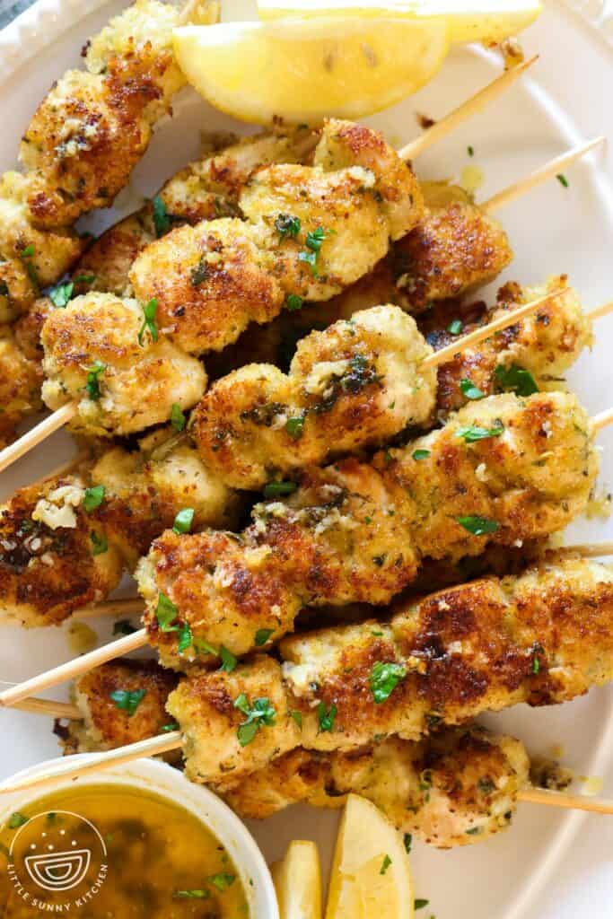 a platter of chicken spiedini skewers with a side of sauce.