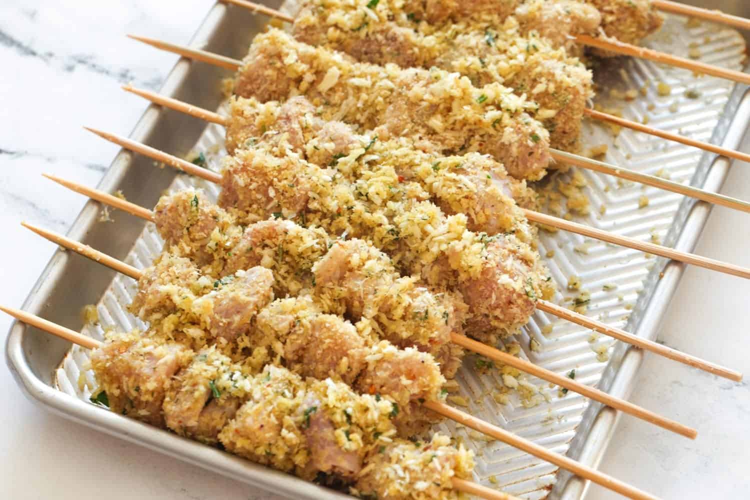 chicken spiedini pieces on wooden skewers, set in a small metal tray.
