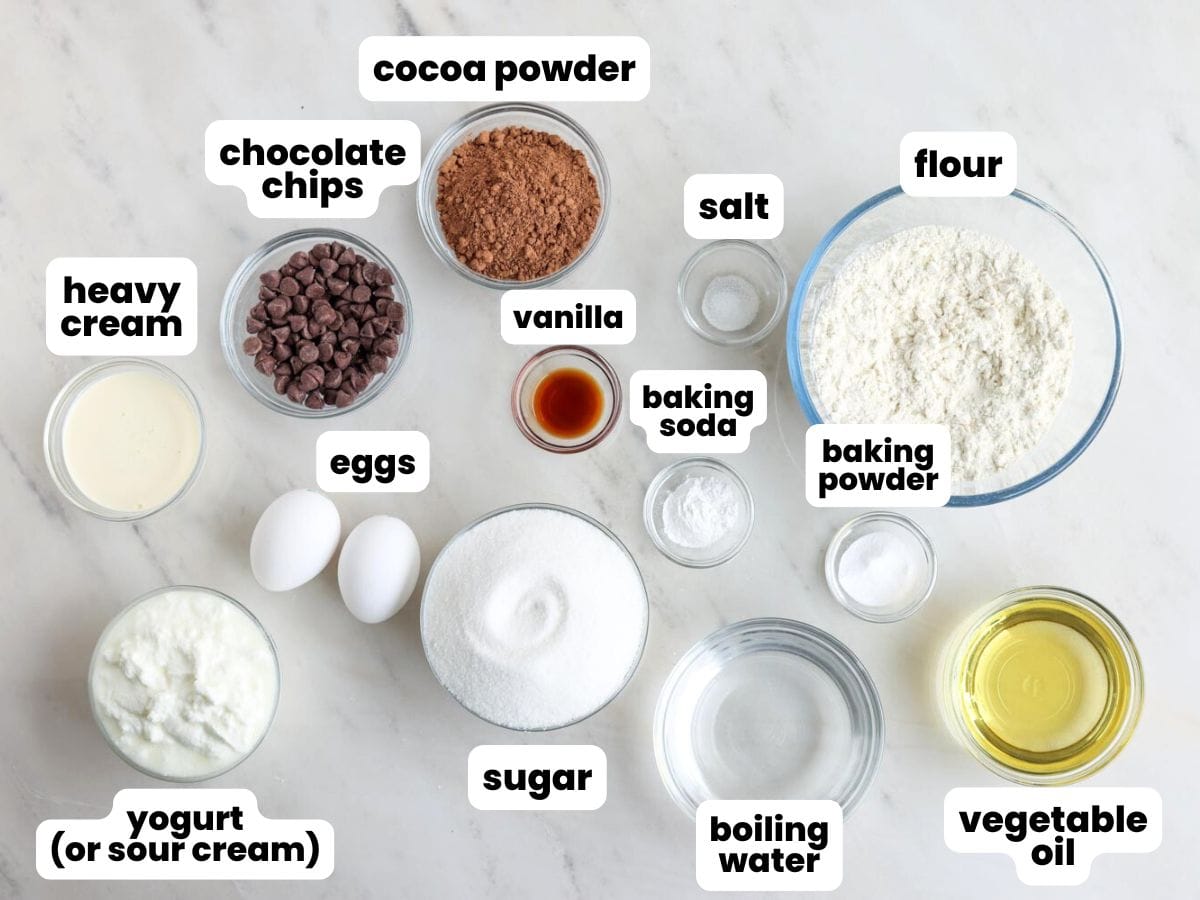 The ingredients for chocolate bundt cake, arranged in small bowls on a marble counter. 