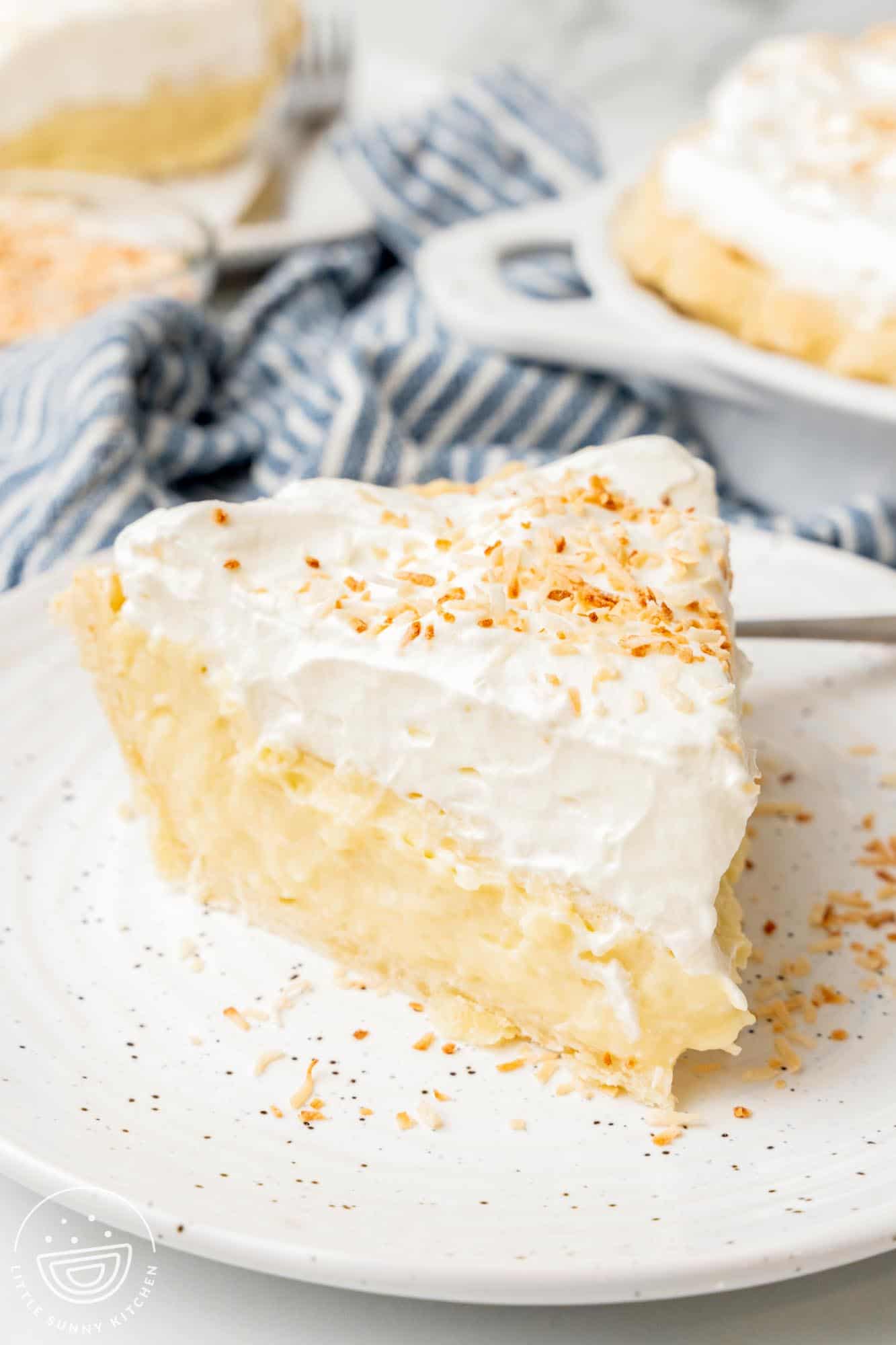 a generous slice of coconut cream pie on a white ceramic plate.