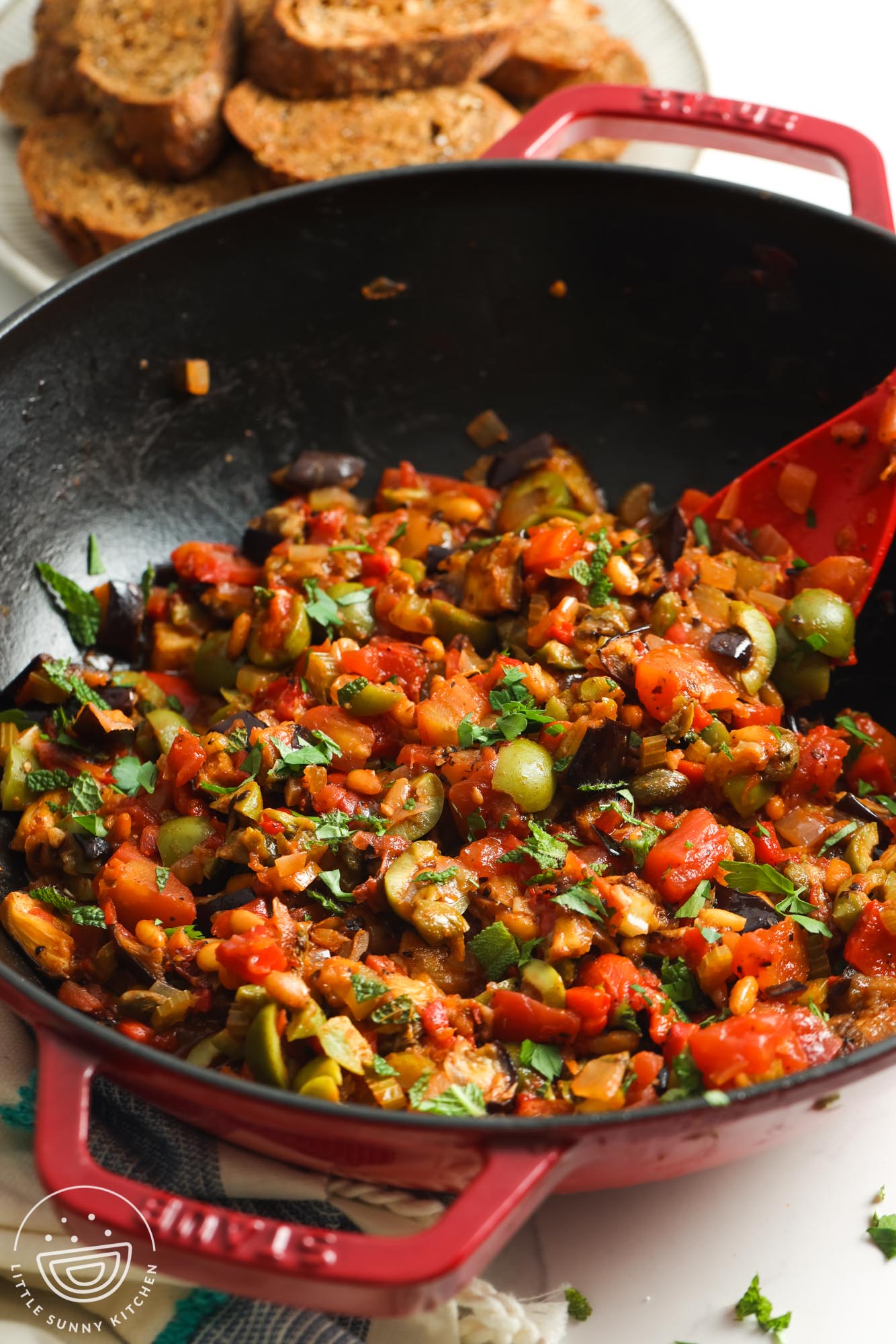 olive and eggplant caponata in a large skillet, garnished with chopped herbs.