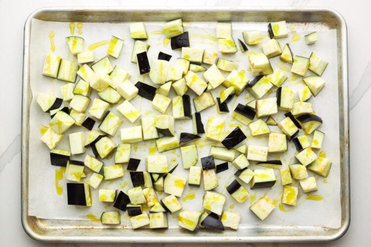 diced eggplant on a parchment lined baking sheet, drizzled with olive oil.