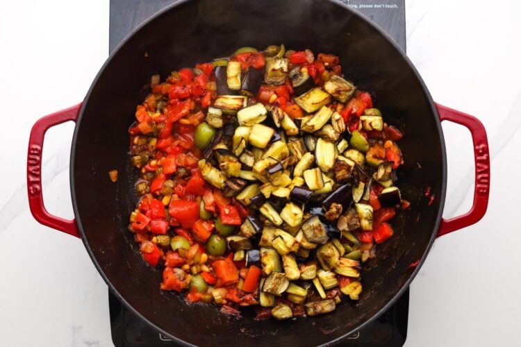 roasted eggplant pieces added to caponata mixture in a skillet.
