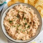 a platter of potato chips with a large bowl of homemade caramelized onion dip on the left side.